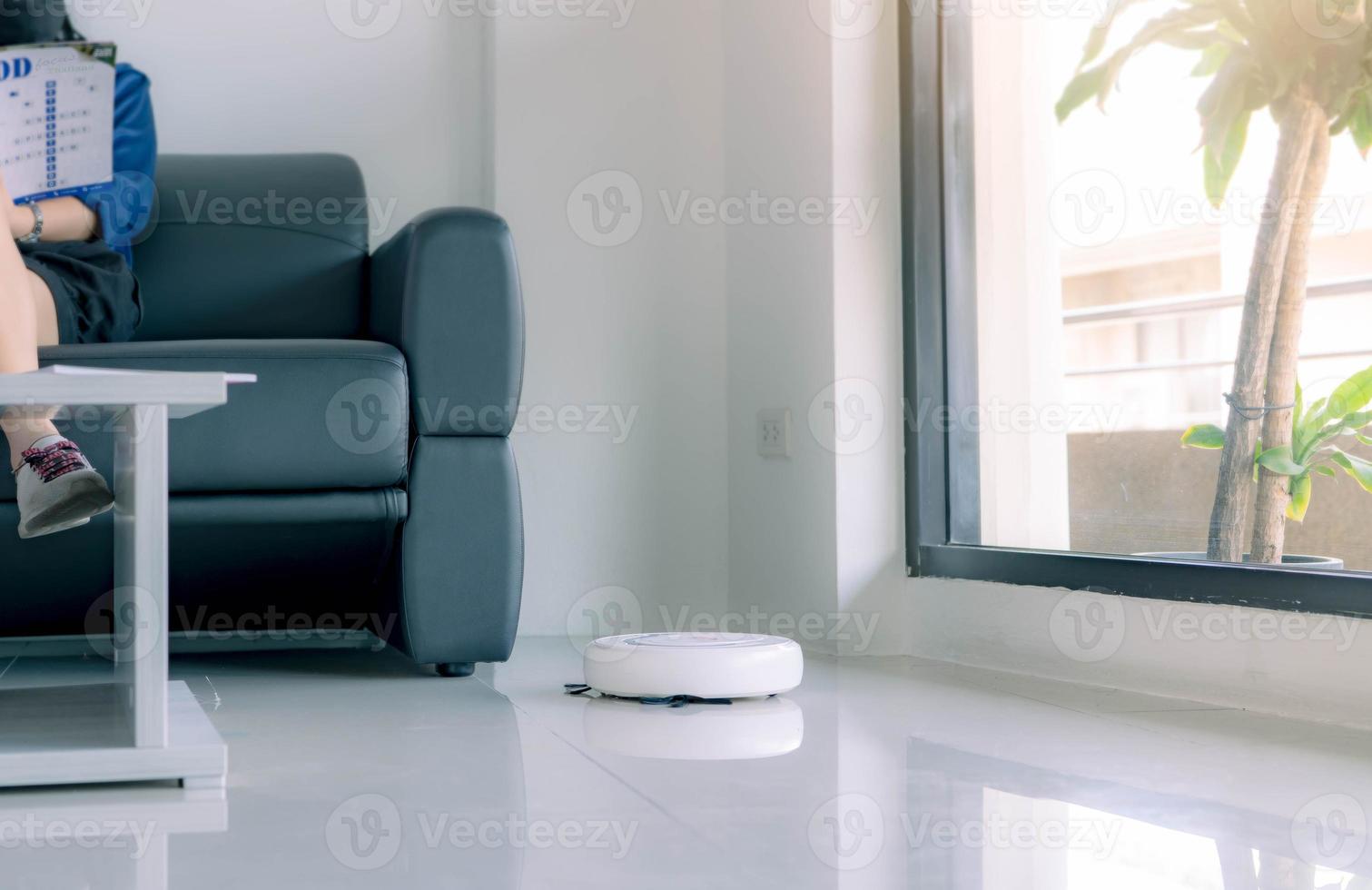 robô aspirador de pó limpando o chão na sala de estar. aspirador de pó robô branco para o conceito de casa inteligente. robô de limpeza para limpeza de piso. dispositivo wireless. tecnologia de limpeza inteligente. aparelho doméstico. foto