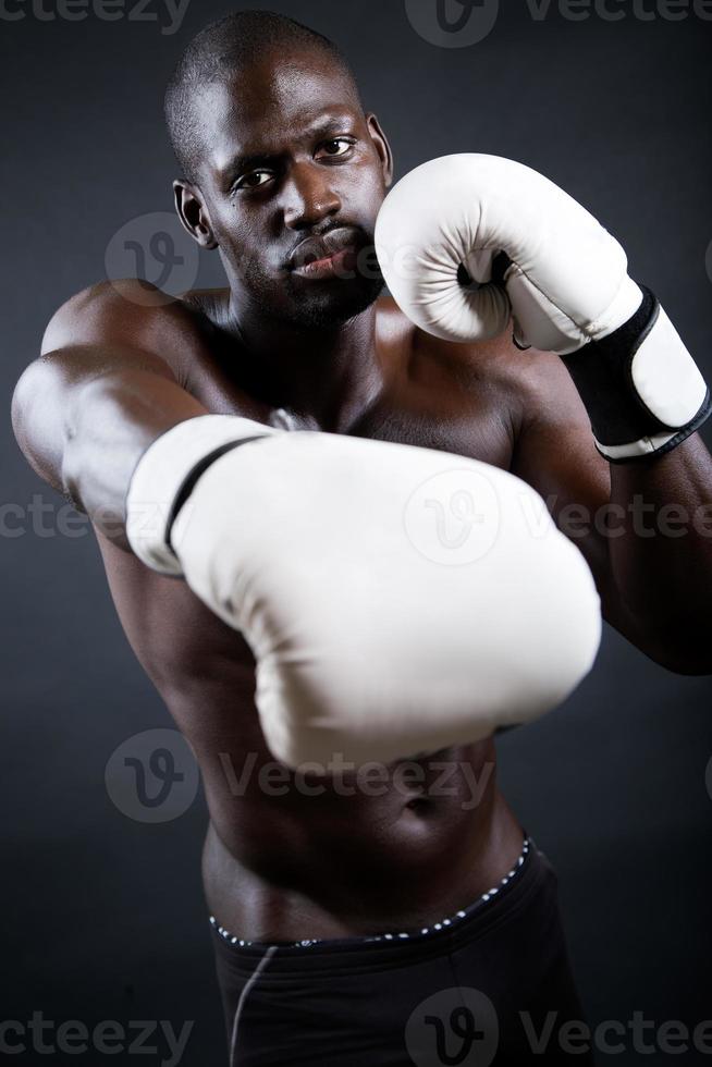 jovem boxeador atlético usando luvas em fundo preto. foto