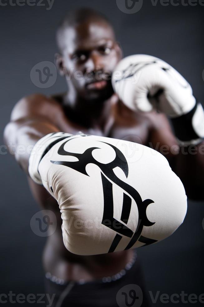 jovem boxeador atlético usando luvas em fundo preto. foto
