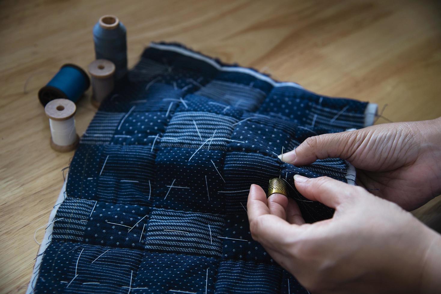 pano de costura de mulher vintage à mão com bordado em fundo de mesa de madeira - pessoas e conceito de trabalho doméstico diy feito à mão foto