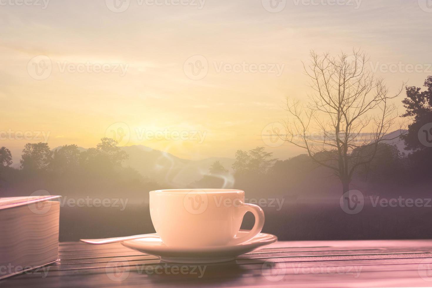café quente e um livro na mesa de madeira ao nascer do sol no jardim foto