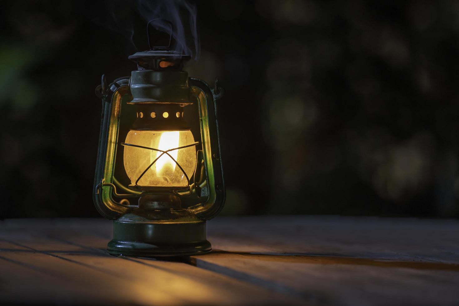 lâmpada de querosene antiga com luzes no chão de madeira à noite foto