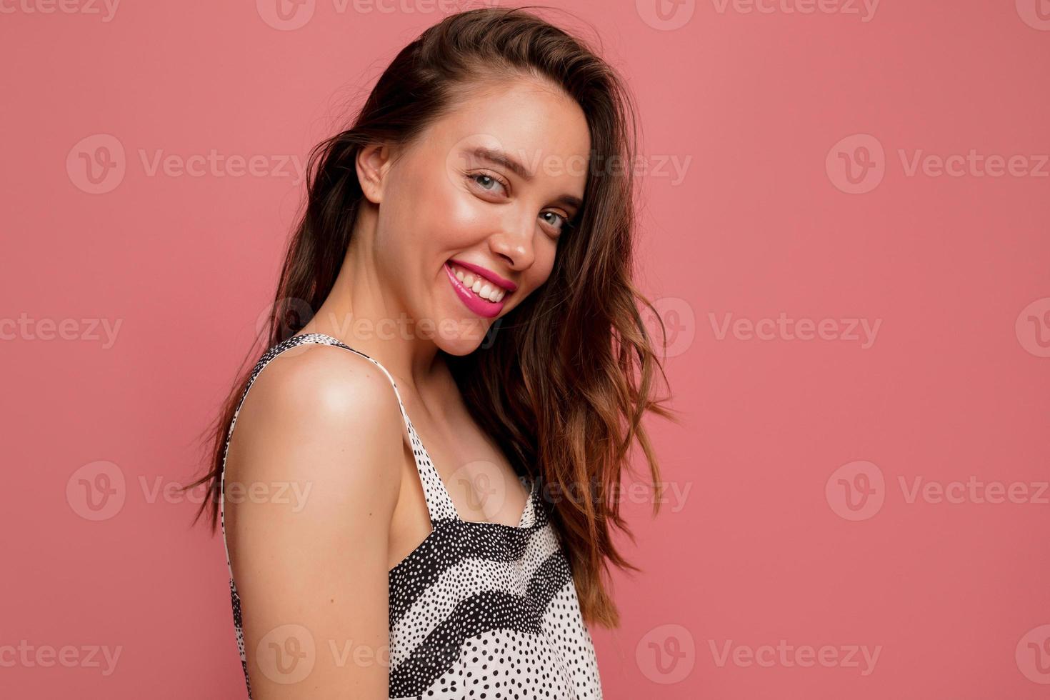 retrato de uma jovem feliz com maquiagem brilhante isolada sobre fundo rosa, vestindo roupa de verão, curtindo a sessão de fotos, emoções verdadeiras felizes foto