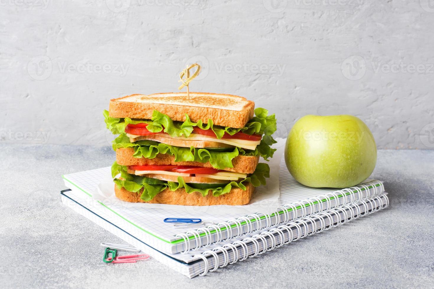 almoço saudável para a escola com sanduíche, maçã fresca. material escolar colorido sortido. copie o espaço. foto