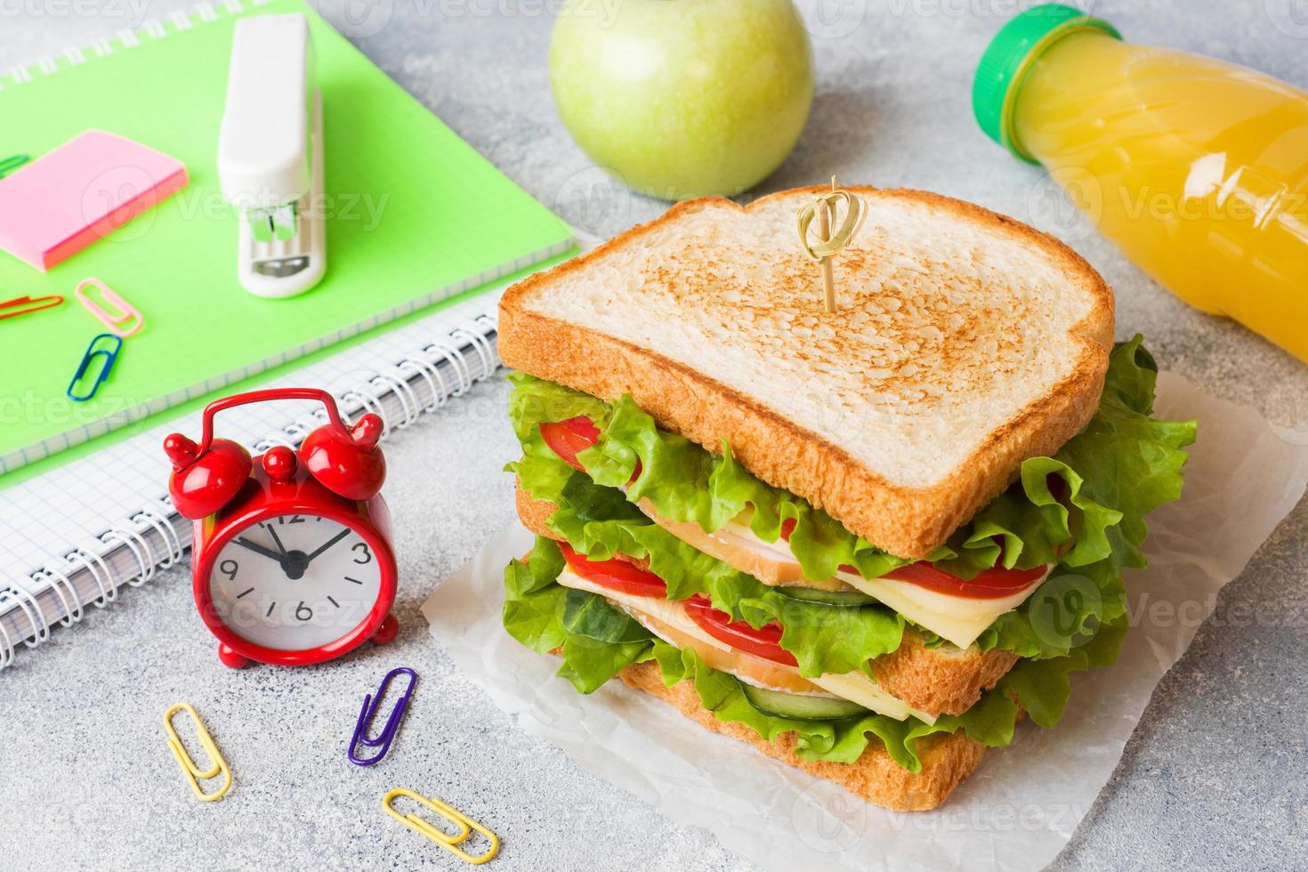 almoço saudável para a escola com sanduíche, maçã fresca e suco de laranja. material escolar colorido sortido. copie o espaço. foto