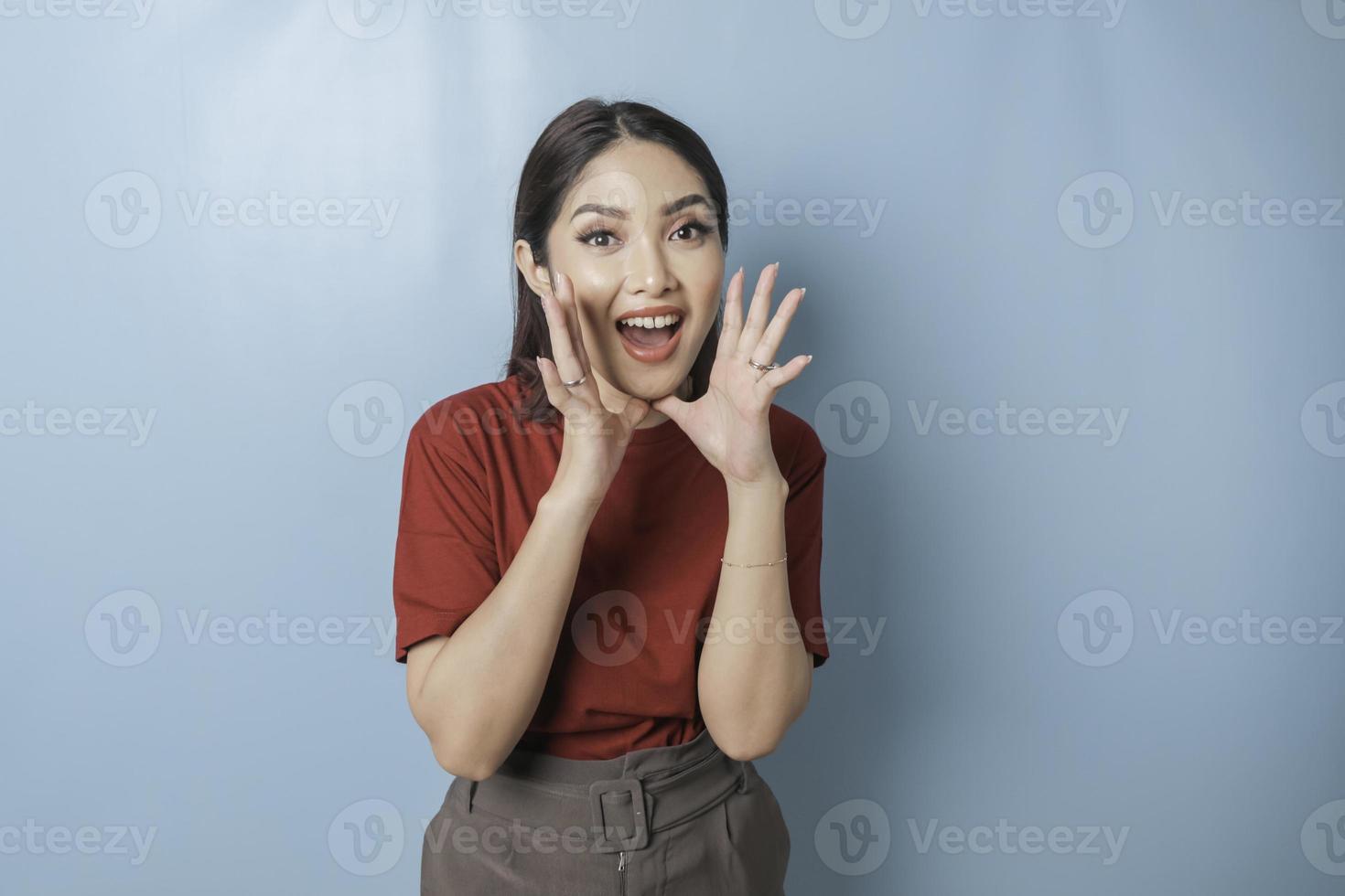 um retrato de uma mulher asiática animada vestindo t-shirt de leitura gritando, isolado por fundo azul foto