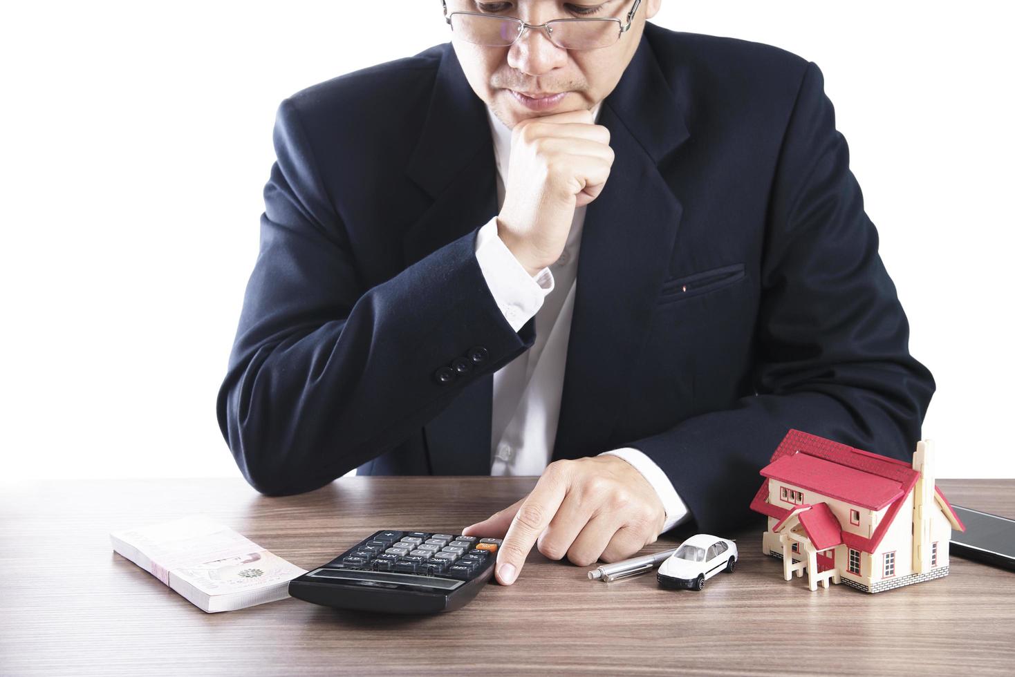 homem de negócios está usando calculadora pensando em dinheiro para pagamento de casa e carro - pessoas com conceito de seguro financeiro imobiliário foto