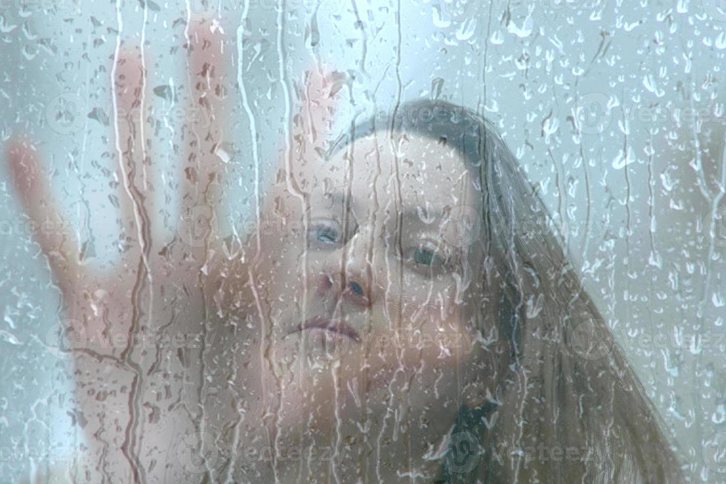 triste mulher deprimida solitária. a menina senta-se na frente da janela chuvosa esperando que pare de chover foto