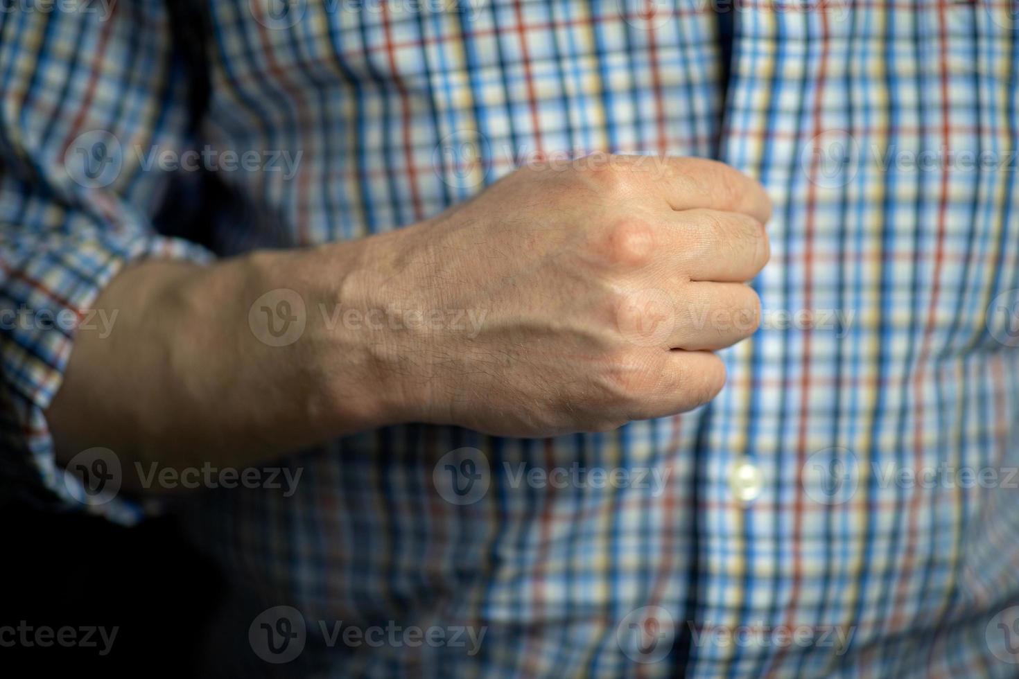 um homem aperta os botões de uma camisa xadrez com a mão direita foto