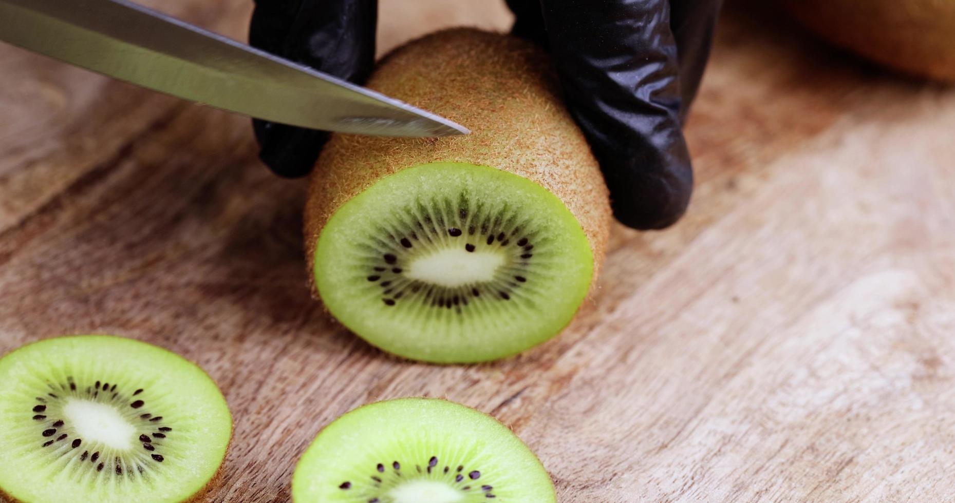 corte o kiwi verde em fatias em uma placa de madeira foto