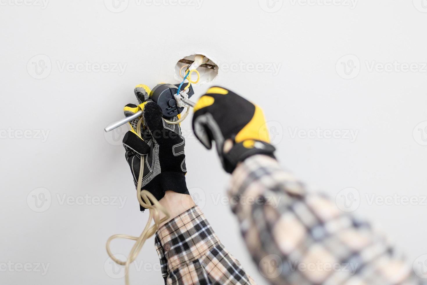 eletricista consertando suspensão da lâmpada do teto foto