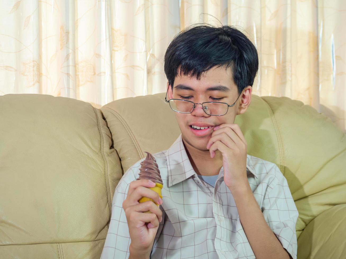jovem asiático com dentes sensíveis e sorvete frio porque comendo sorvete na sala de estar. foto