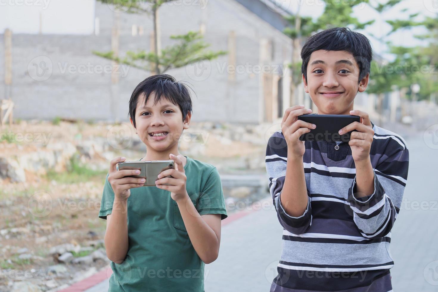 duas crianças com gadgets. irmãos navegando na net ou jogando jogos online no smartphone e tablet digital do lado de fora em pé. comunicação moderna e conceito de vício em gadget. foto