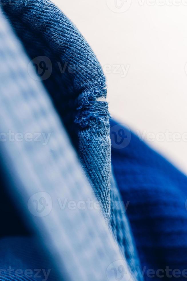 close-up no jiu jitsu brasileiro ou uniforme de quimono azul judô pendurado ao lado de uma parede foto