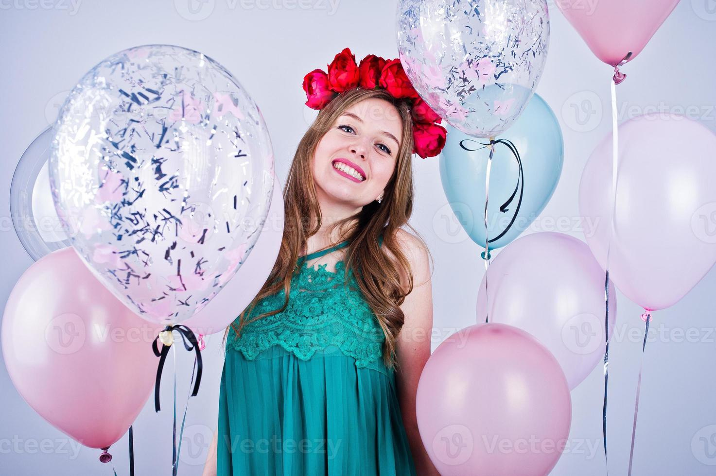 garota feliz no vestido verde turquesa e grinalda com balões coloridos isolados no branco. comemorando o tema do aniversário. foto