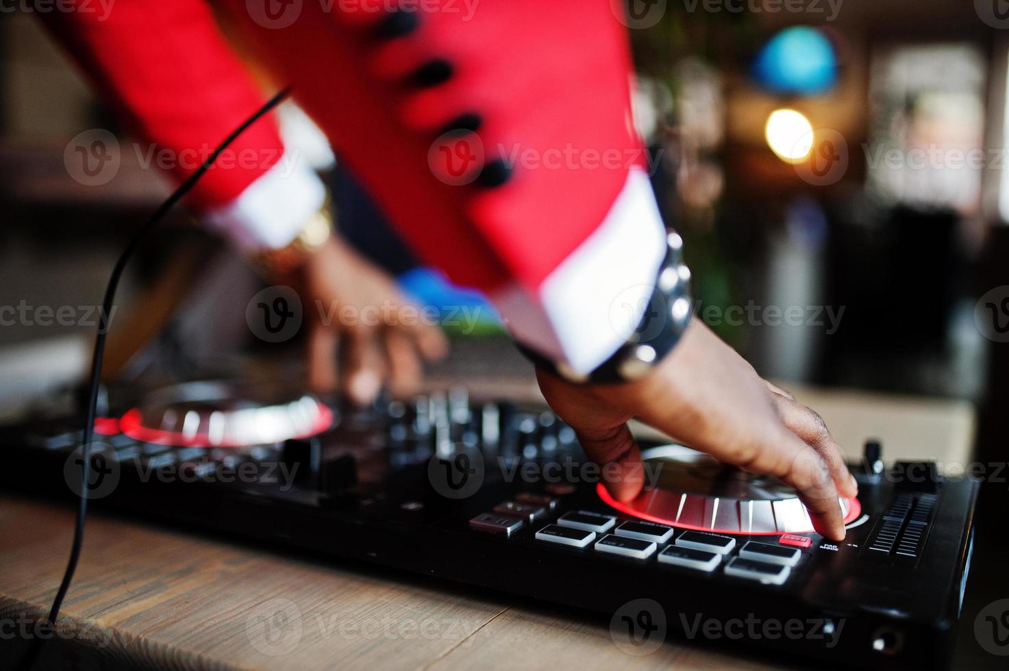 mãos de moda homem afro-americano modelo dj no terno vermelho com controlador de dj. foto