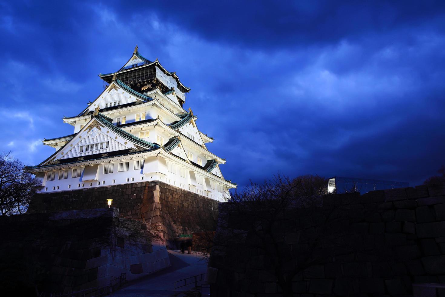 castelo de osaka em osaka, japão, iluminado por holofotes durante o anoitecer. foto