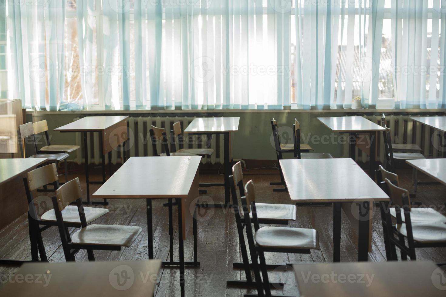carteiras para alunos da escola. sala de aula está vazia. cadeiras e mesas estão em fila. foto