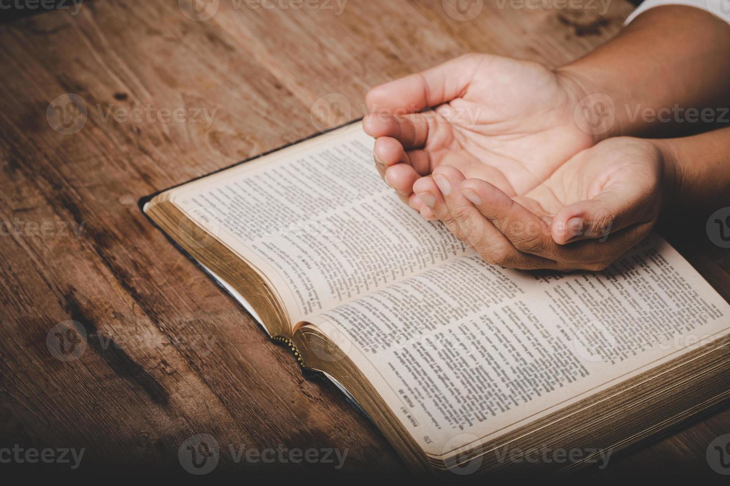 close-up da mão da mulher cristã na bíblia sagrada são orar e adorar para agradecer a Deus na igreja com fundo preto, conceito de fé, espiritualidade e religião foto