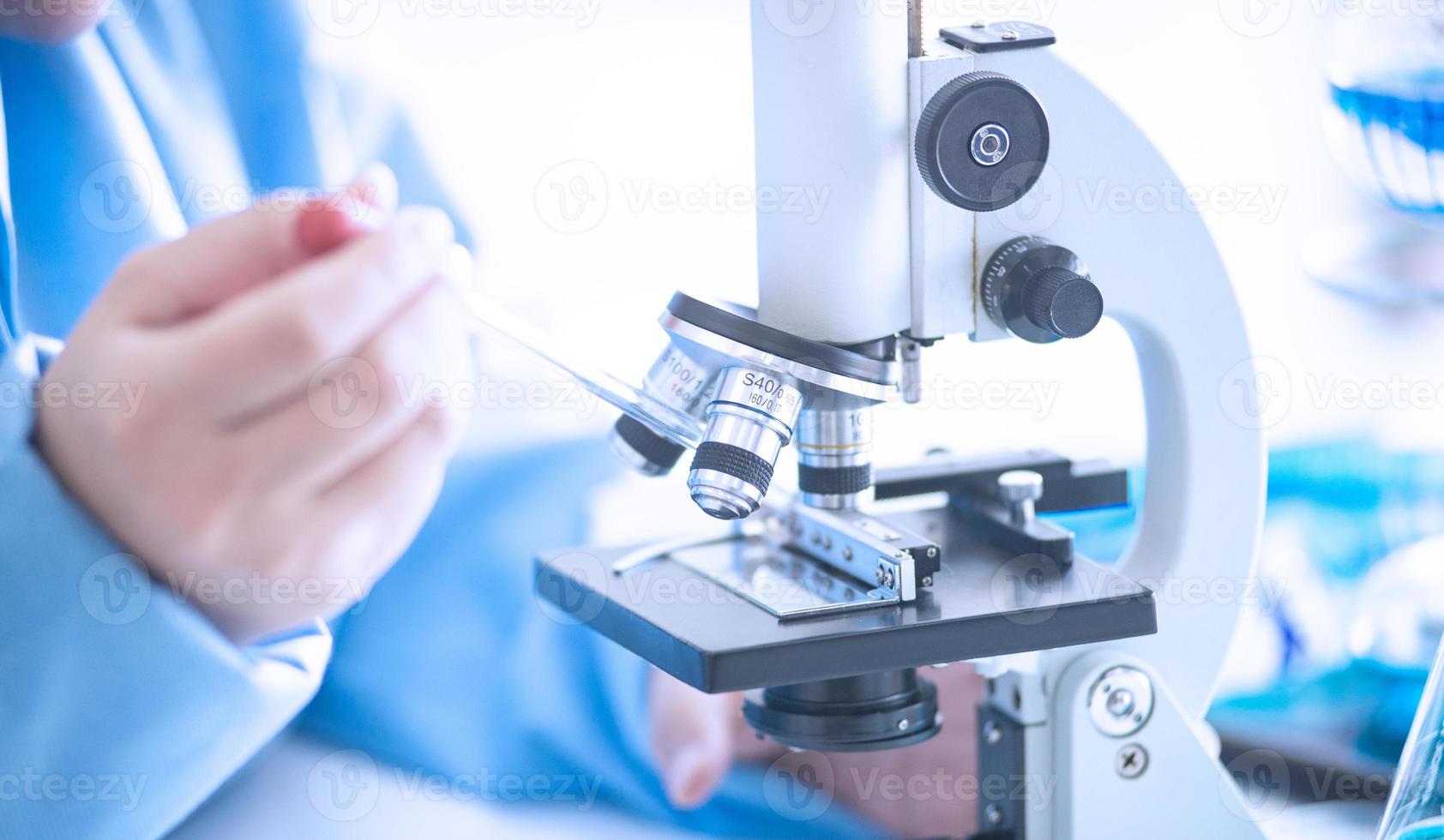 mulher asiática cientista, pesquisadora, técnica ou estudante realizou pesquisas ou experimentos usando microscópio que é equipamento científico em laboratório médico, de química ou biologia foto