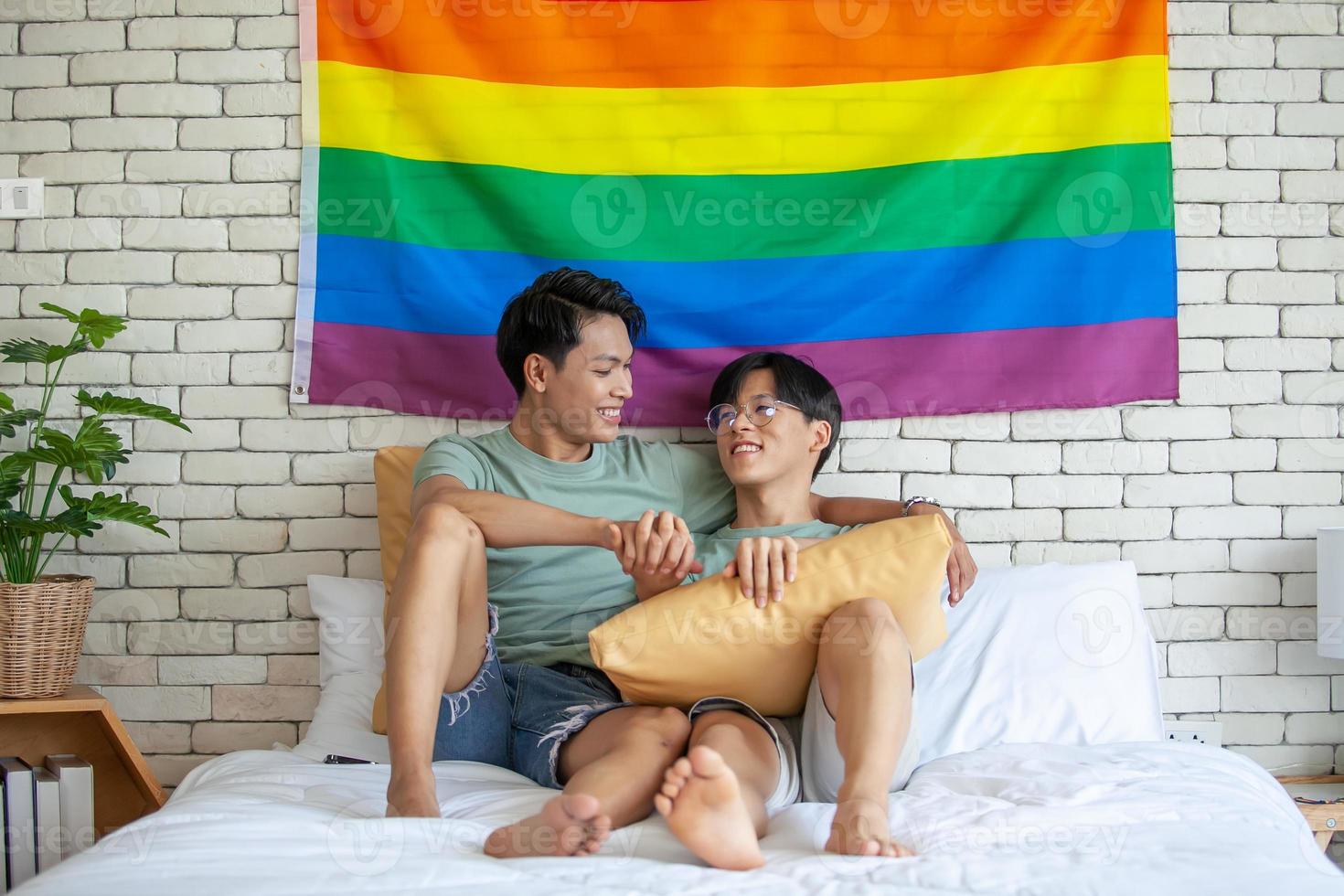 feliz casal gay asiático de mãos dadas relaxando em casa na cama, conceito lgbtq. foto