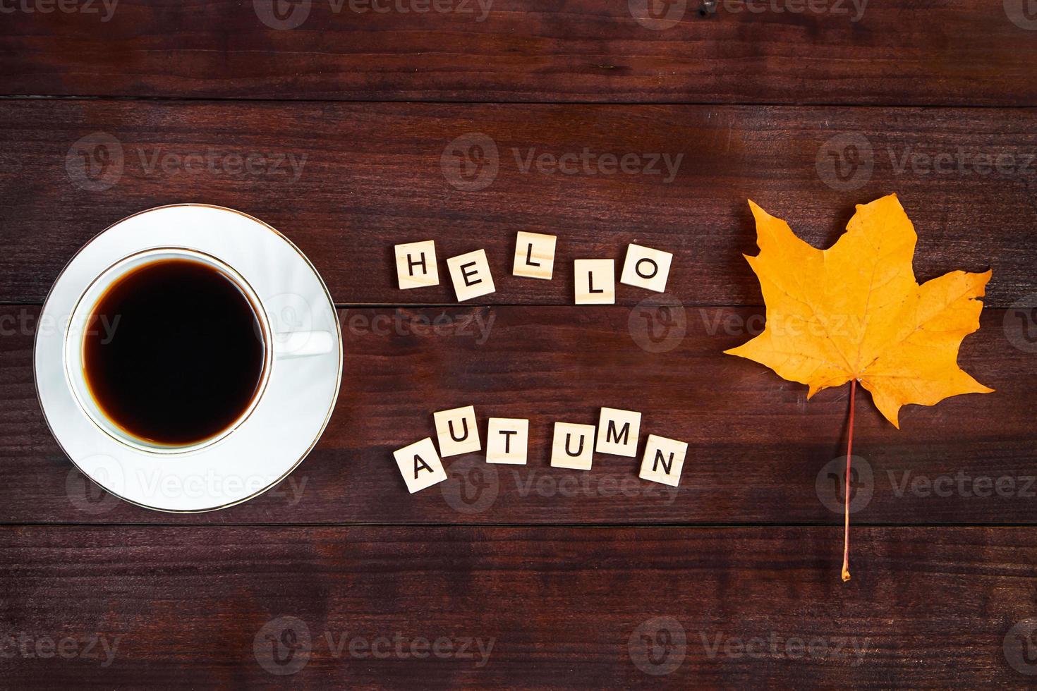 Olá conceito de outono. xícara de café e folhas caídas sobre fundo de madeira marrom. bebida quente para o frio. foto