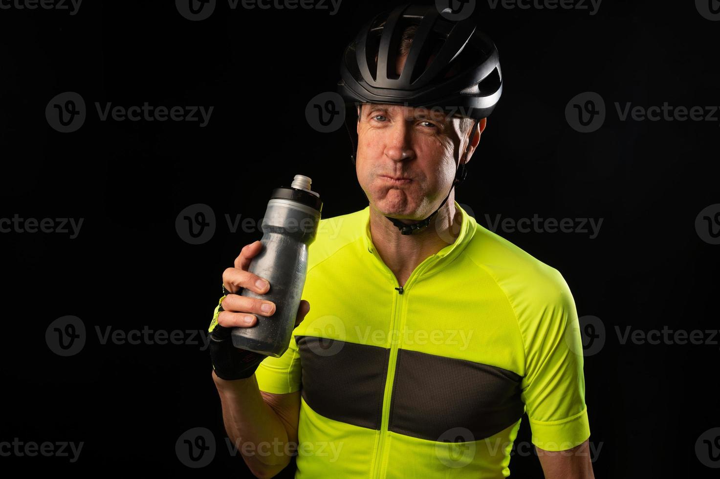 ciclista maduro bebendo de uma garrafa de água em um fundo preto com espaço de cópia com espaço de cópia foto