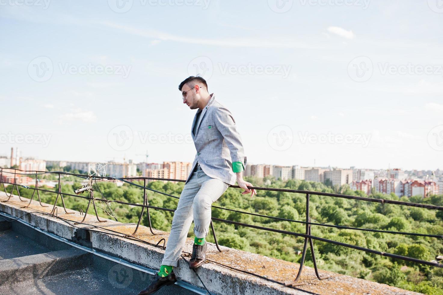 homem macho elegante sonhador de terno cinza e óculos posou no telhado. foto