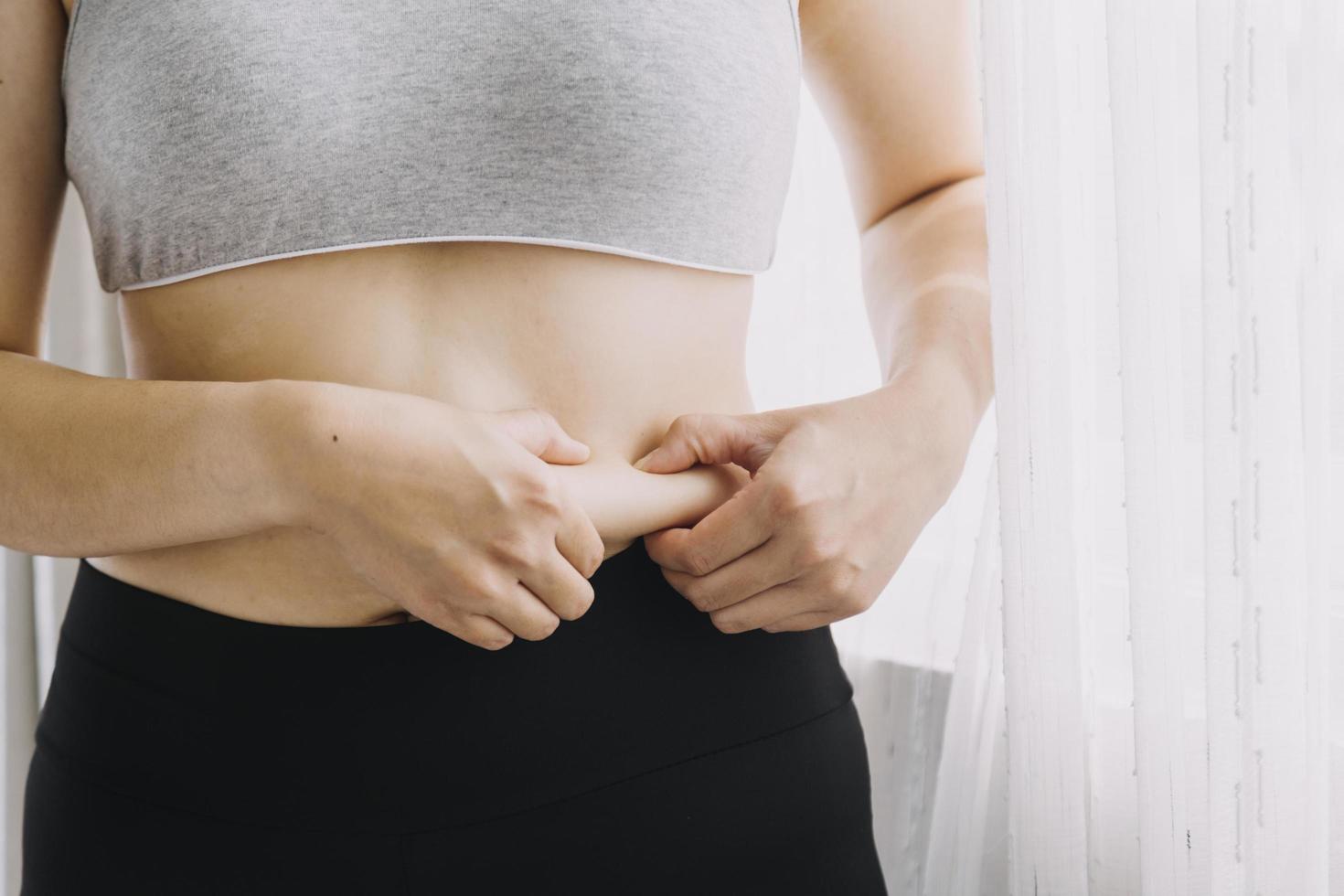 linda mulher gorda com fita métrica ela usa a mão para espremer o excesso de gordura que está isolado em um fundo branco. ela quer perder peso, o conceito de cirurgia e quebrar a gordura sob o foto