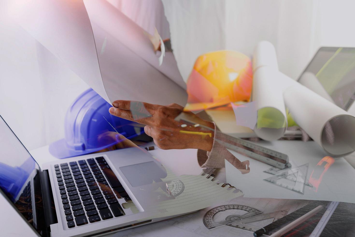 dois colegas discutindo dados de trabalho e tablet, laptop com projeto arquitetônico no canteiro de obras na mesa no escritório foto