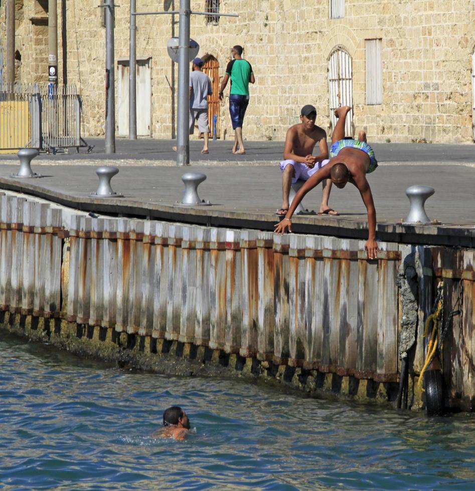 tel aviv, israel - 12 de setembro de 2019 - meninos escapando do calor do verão pulando na baía em tel aviv foto