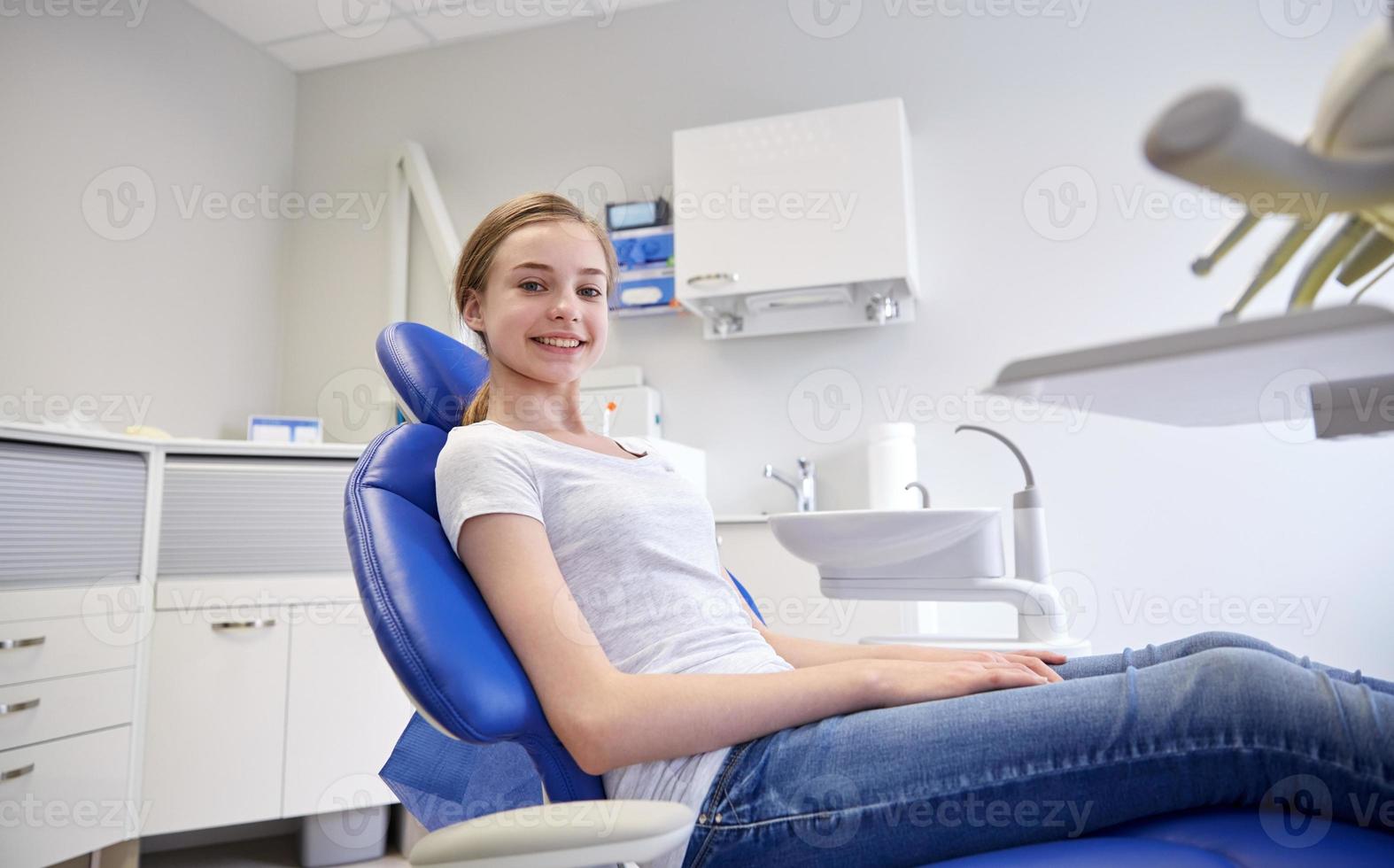 menina paciente feliz no consultório odontológico foto