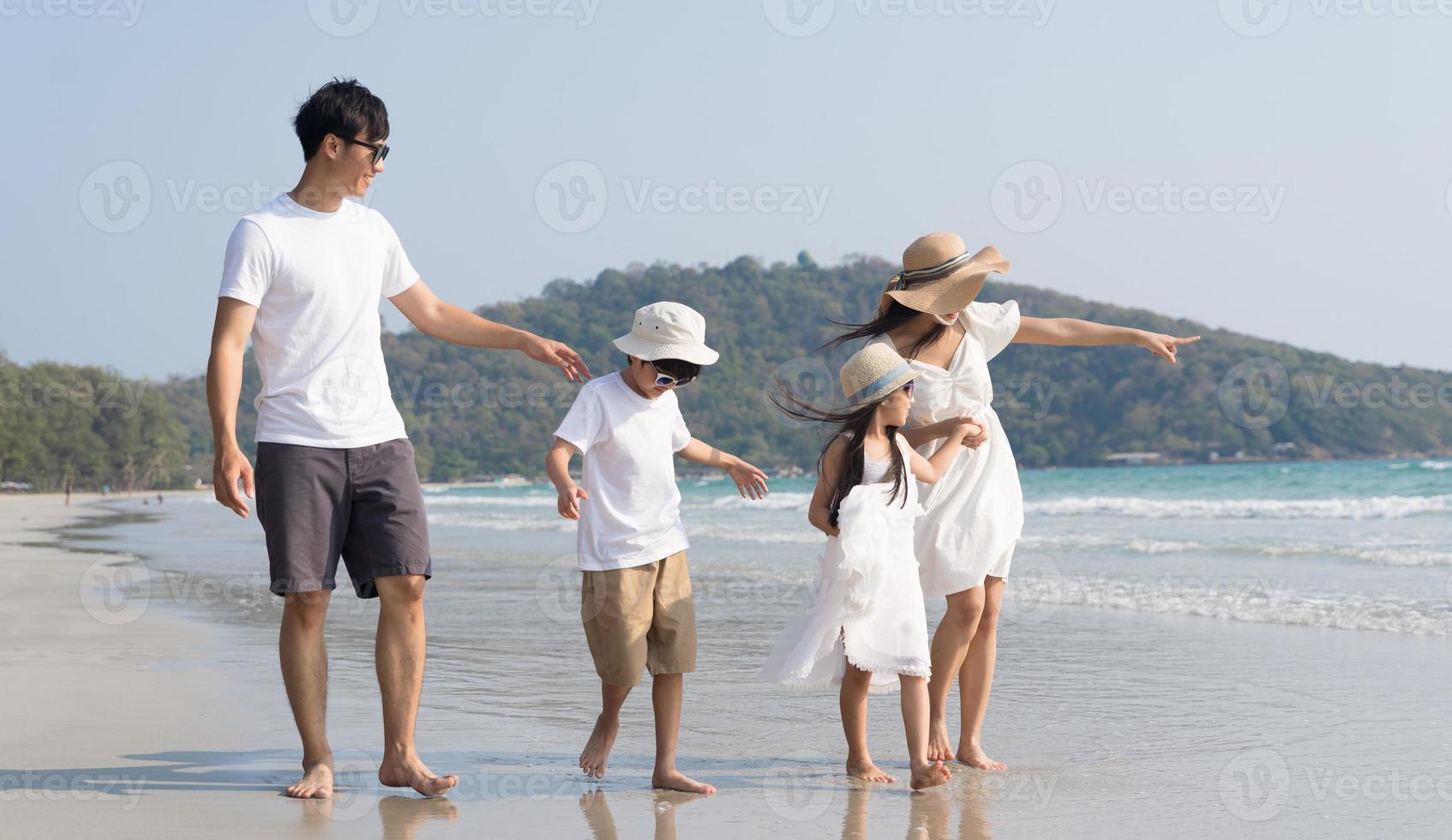 família asiática andando na praia com crianças conceito de férias felizes foto