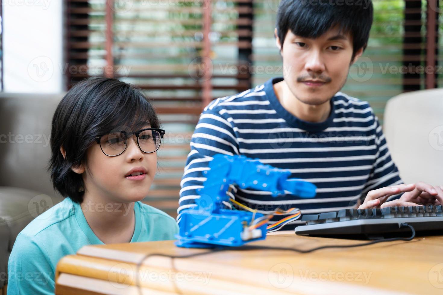 crianças asiáticas programam guindastes robóticos com laptops para aprender sobre tecnologia, matemática, engenharia. programação e codificação em casa foto