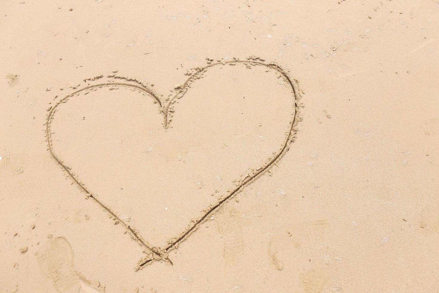 coração desenhado na areia lisa da praia. conceito de amor foto