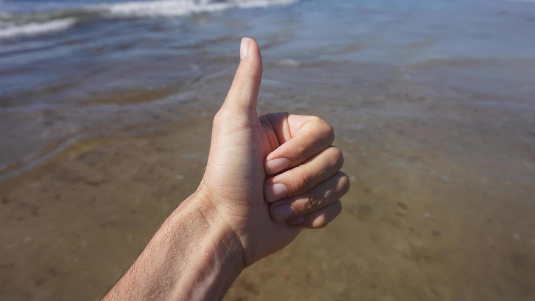 polegares para cima na praia foto