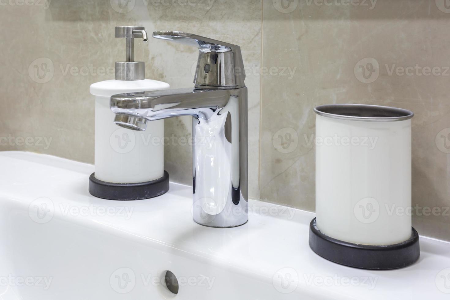 dispensadores de sabonete e xampu perto da pia de cerâmica com torneira no banheiro caro do loft foto