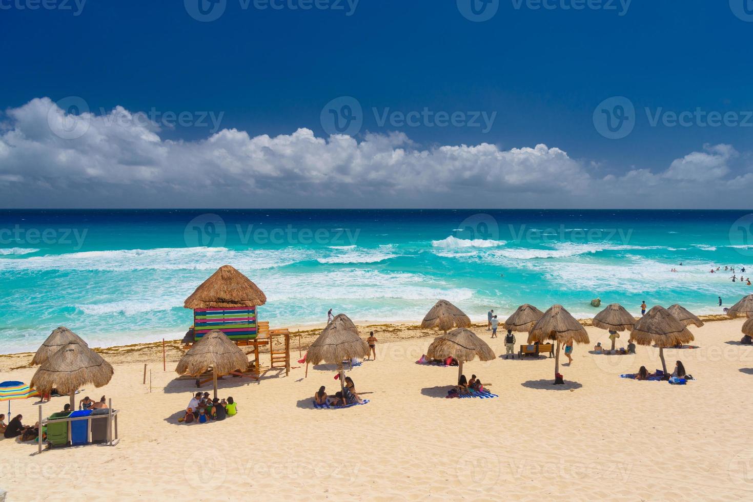 guarda-chuvas em uma praia de areia com água azul em um dia ensolarado perto de cancun, méxico foto