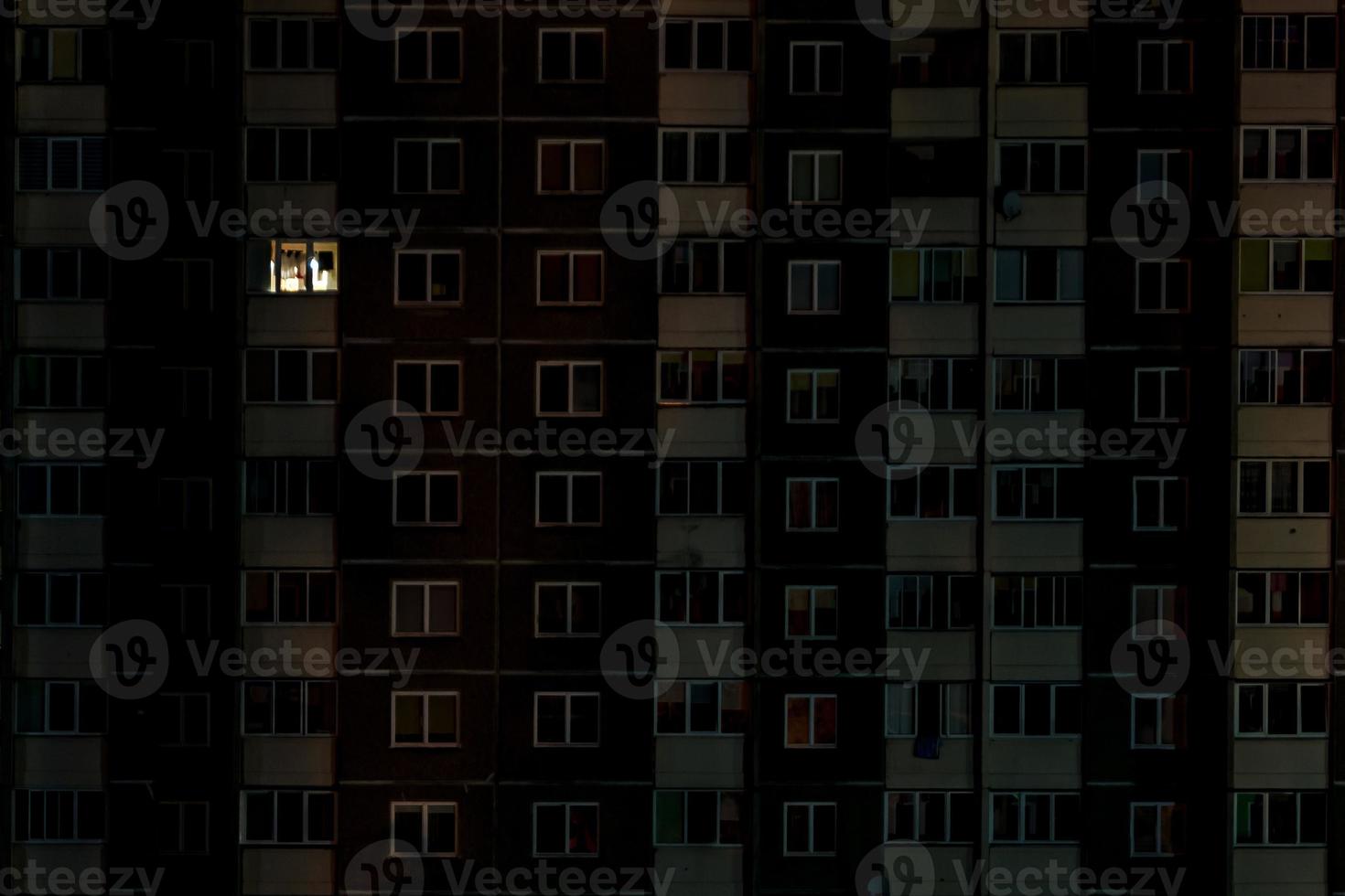 luz em uma única janela. panorama noturno plano de luz multicolorida em janelas de edifícios de vários andares. vida na cidade grande foto