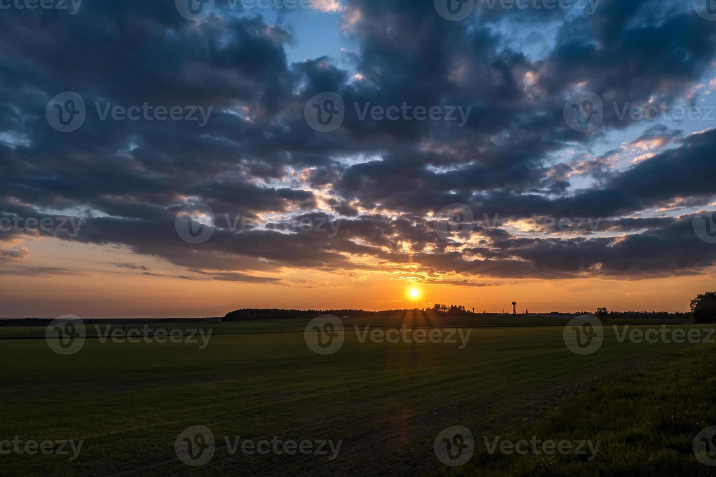 paisagem de campo verde com céu azul vermelho rosa à noite com belas nuvens após o pôr do sol foto