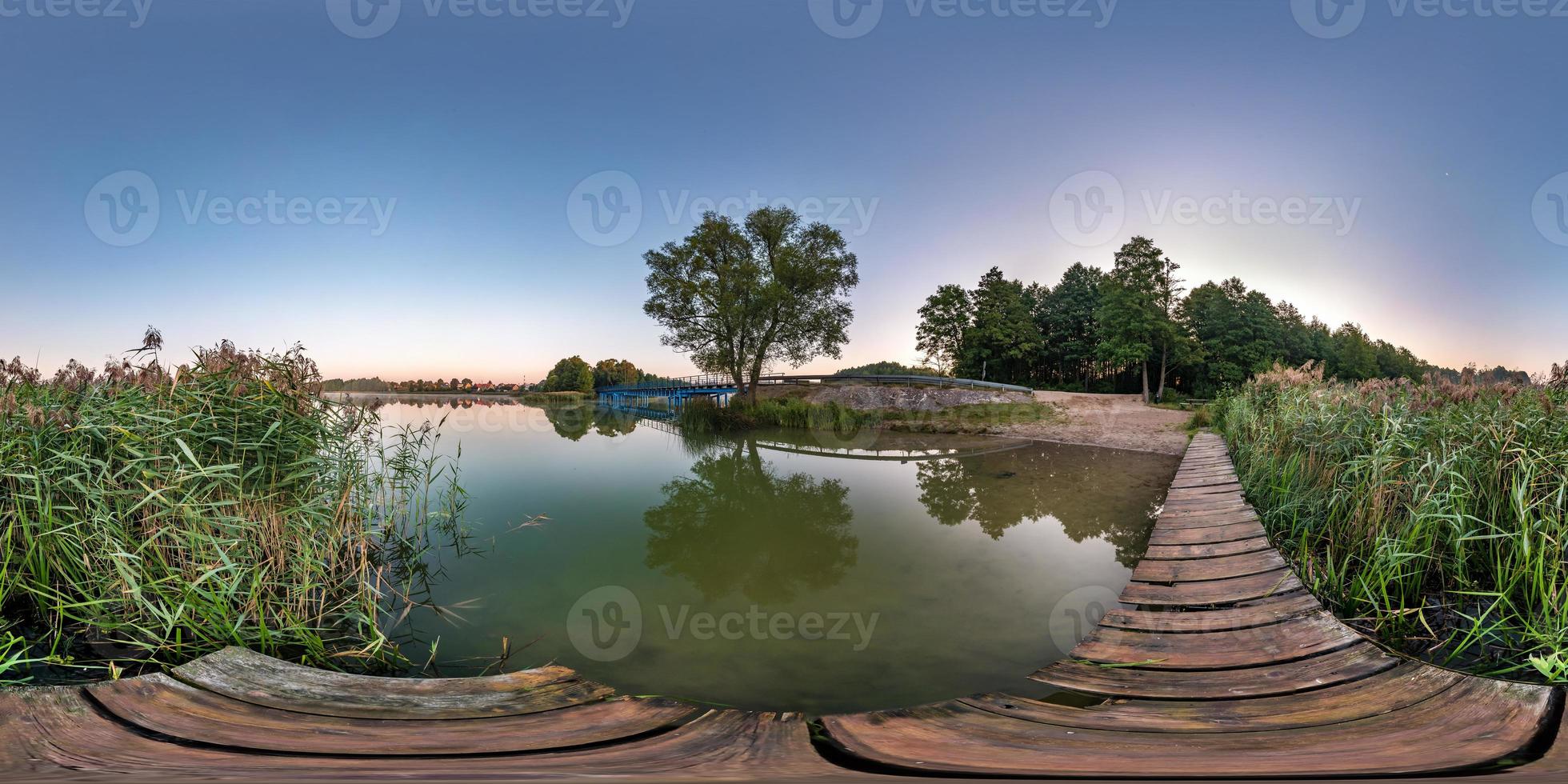 panorama hdri esférico sem costura completo vista de ângulo de 360 graus no cais de madeira do enorme lago ou rio de manhã com nascer do sol rosa com neblina em projeção equirretangular, conteúdo vr foto