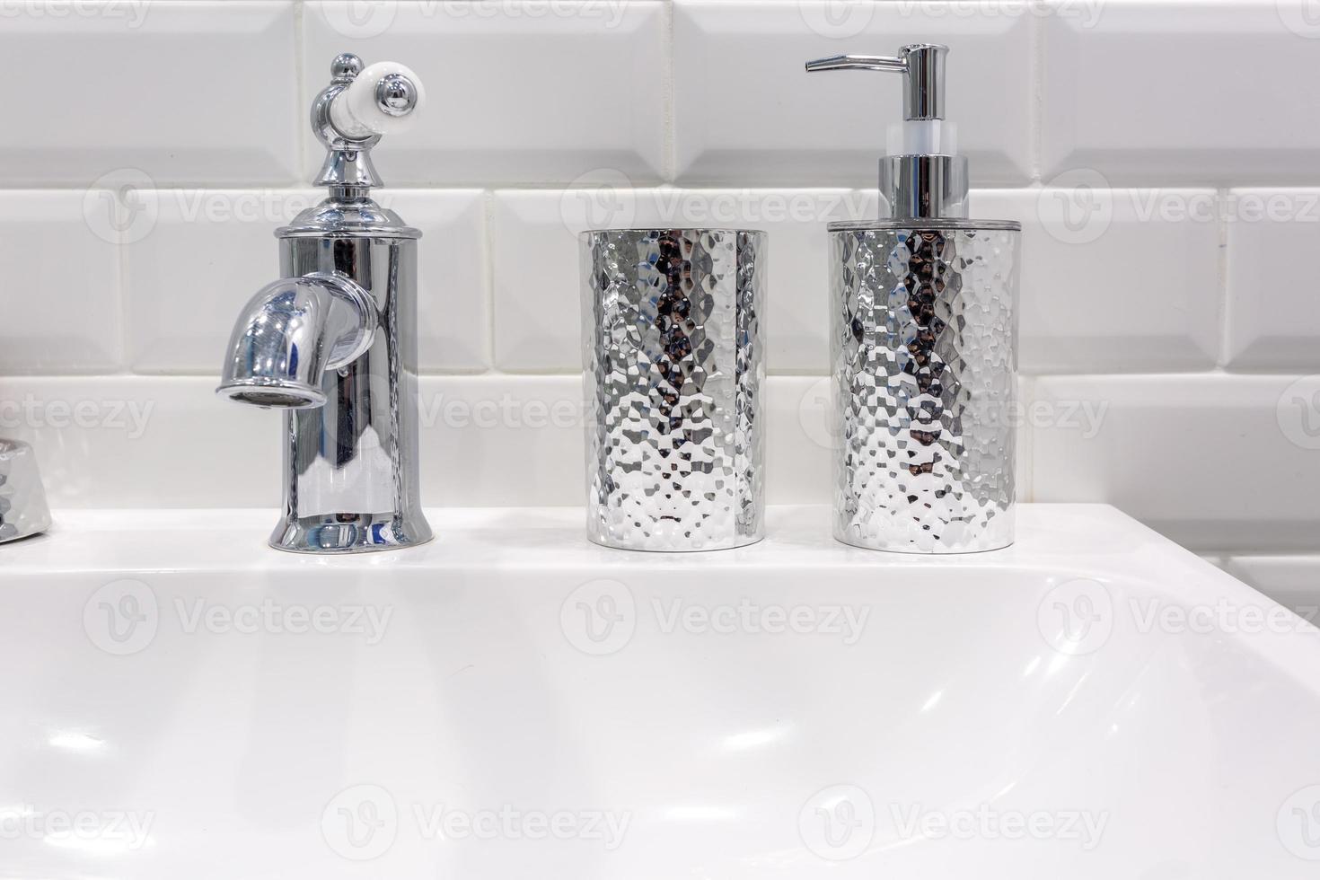 dispensadores de sabonete e xampu perto da pia de cerâmica com torneira no banheiro caro do loft foto