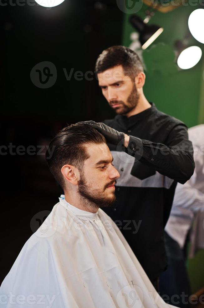 homem barbudo bonito na barbearia, barbeiro no trabalho. foto