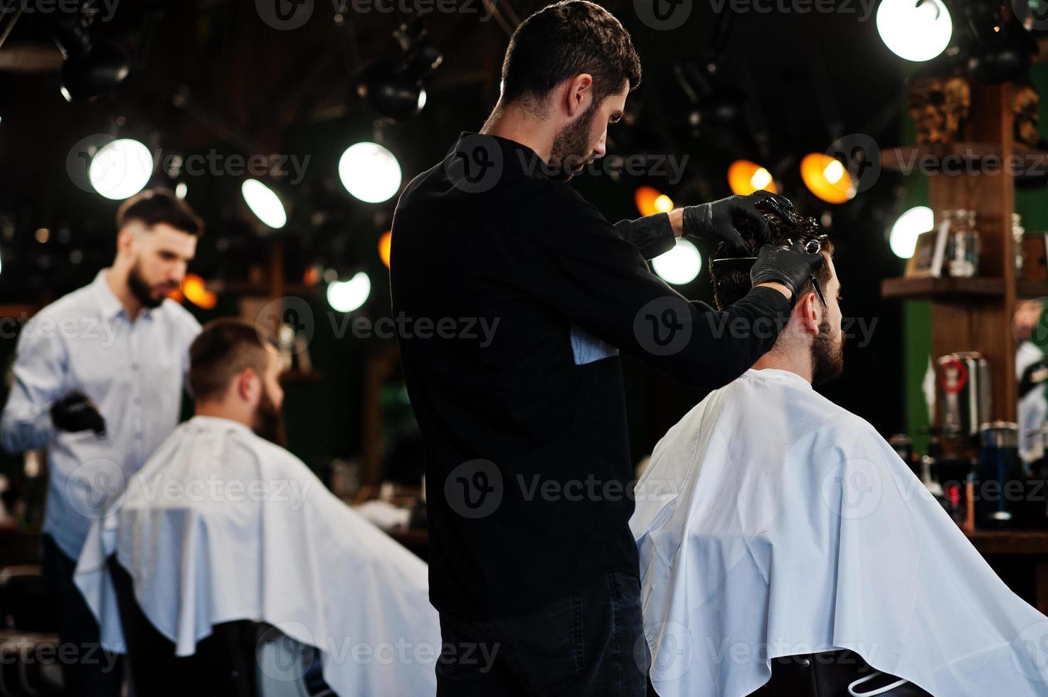 homem barbudo bonito na barbearia, barbeiro no trabalho. foto