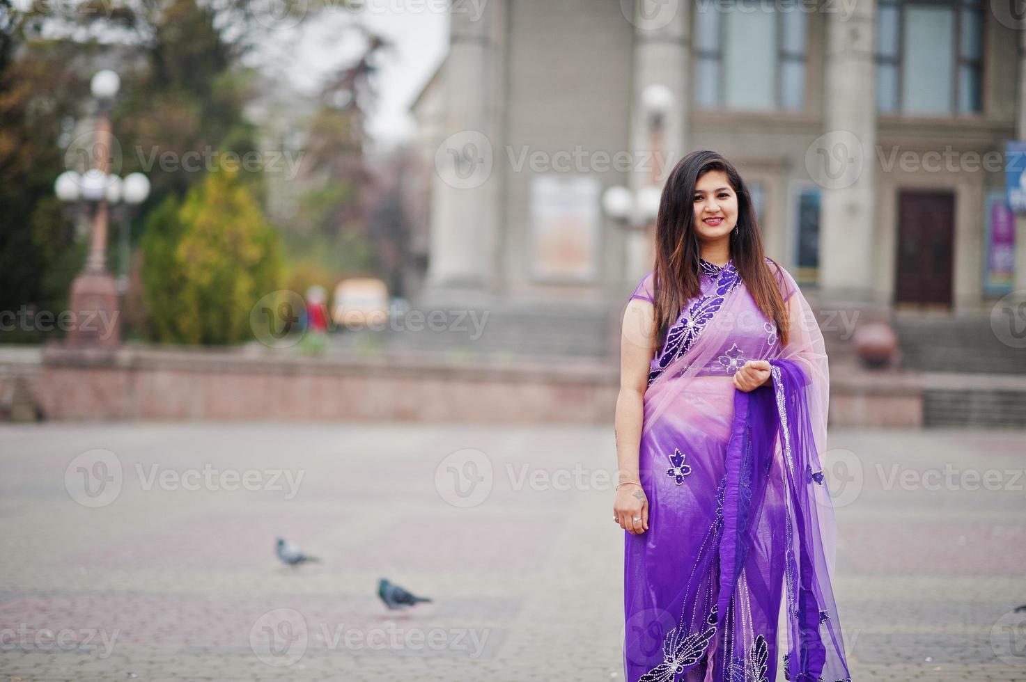 garota hindu indiana no tradicional saree violeta posou na rua contra pombas. foto