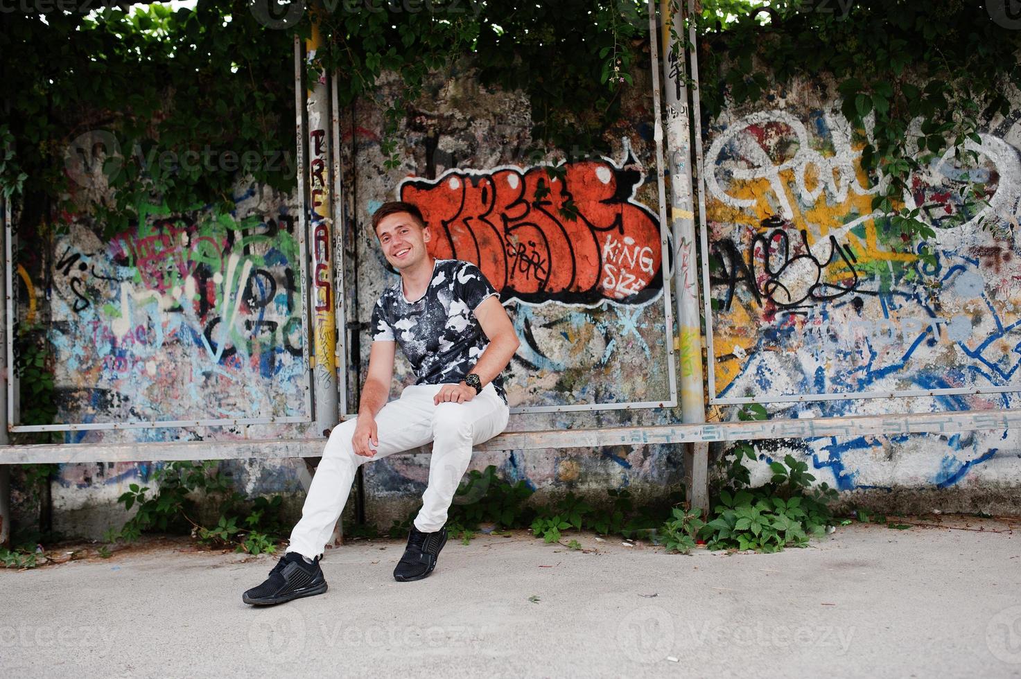 retrato de estilo de vida de homem bonito posando na rua da cidade com parede de graffiti. foto