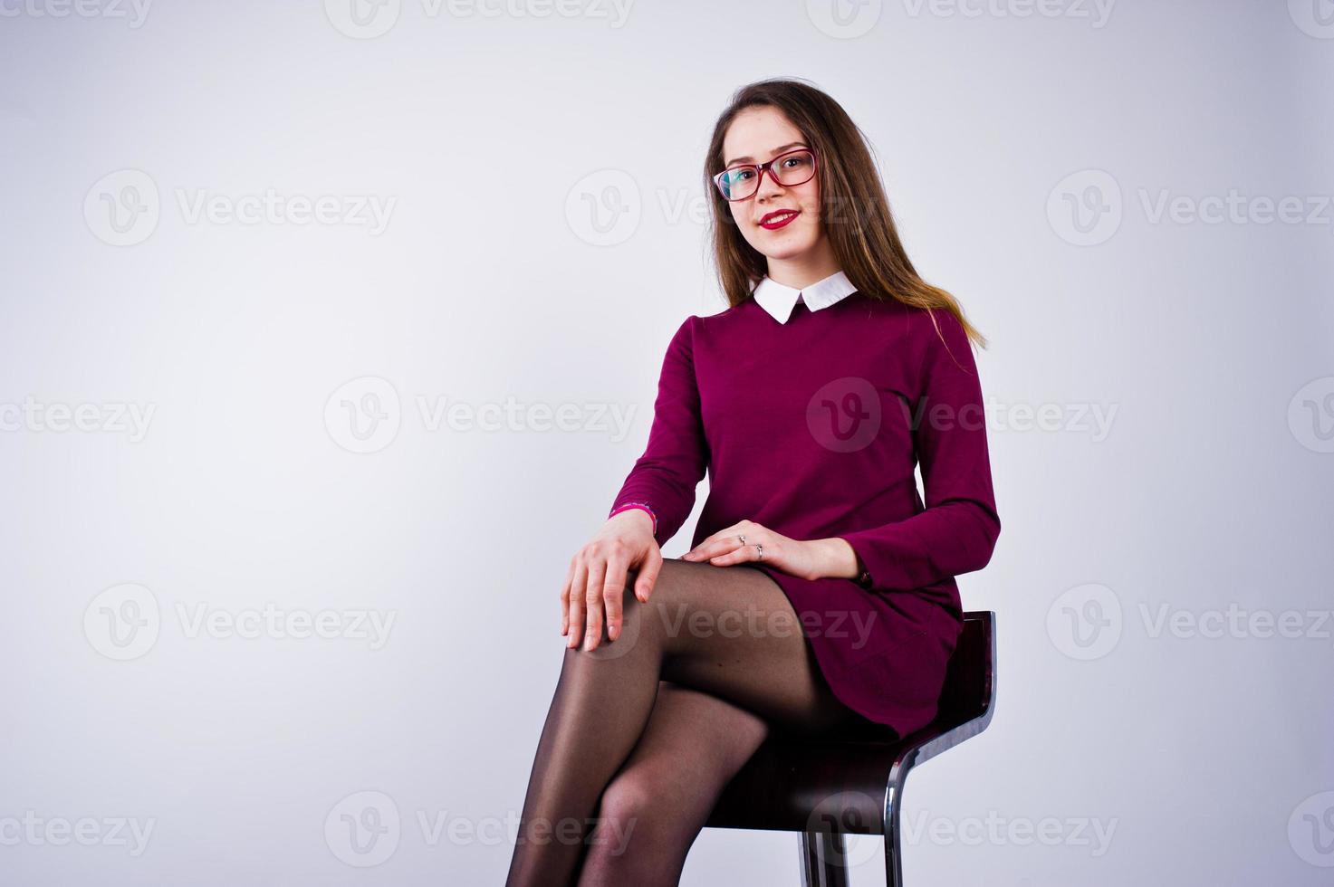 retrato de uma jovem de vestido roxo e óculos, sentado na cadeira no estúdio. foto