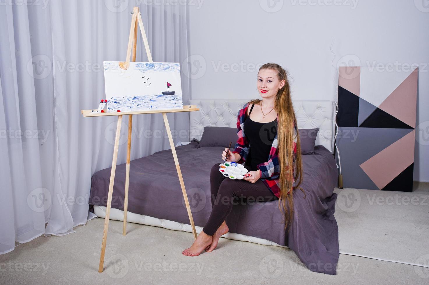 pintor de artista de mulher bonita com pincéis e tela a óleo posando na cama no quarto. foto