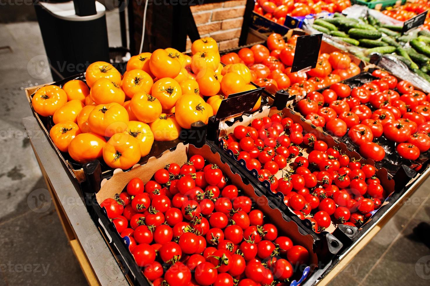 legumes tomates vermelhos e amarelos em caixas no supermercado. foto