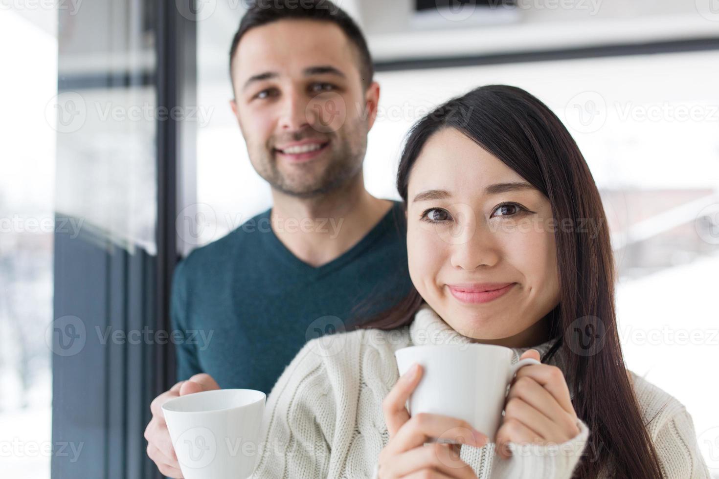 casal multiétnico, desfrutando de café da manhã pela janela foto